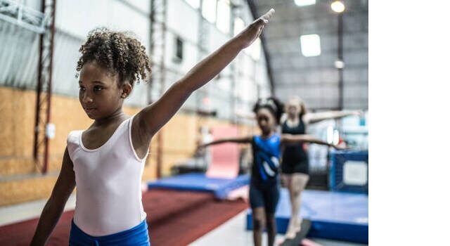 Girl Walking On A Balance Beam In A Gymnasium