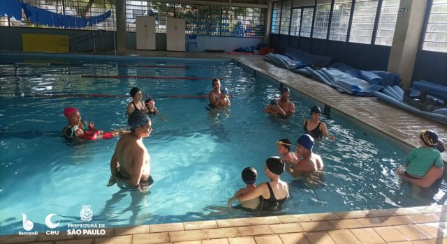 Alunos com seus bebês realizando aula de natação